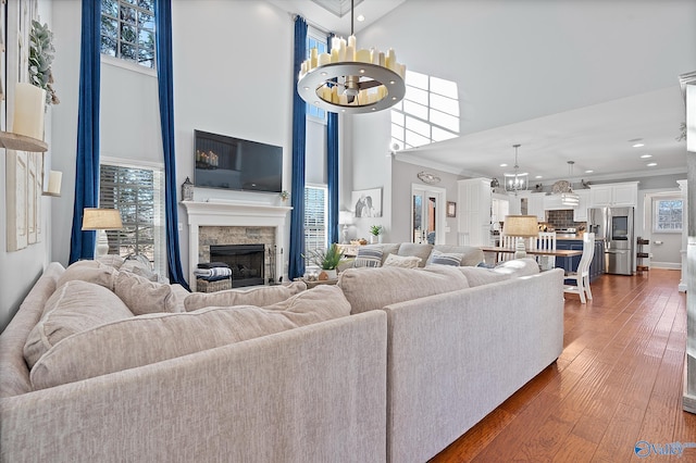 living room with dark wood-type flooring, a high ceiling, ornamental molding, and an inviting chandelier