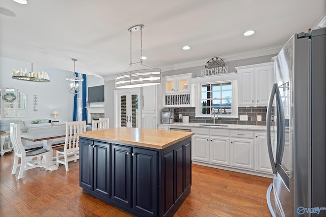 kitchen featuring white cabinets, stainless steel fridge, a center island, and sink