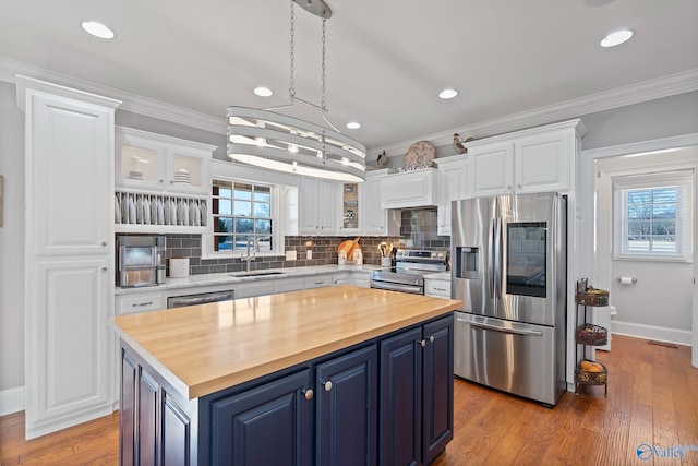 kitchen with white cabinetry, blue cabinets, a center island, ornamental molding, and stainless steel appliances