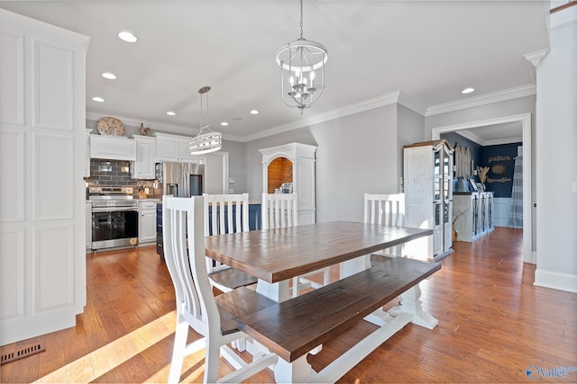 dining room featuring light hardwood / wood-style floors, ornamental molding, and a notable chandelier