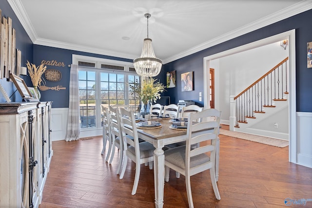 dining area with a notable chandelier, crown molding, and dark wood-type flooring