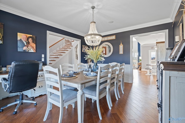 dining space with hardwood / wood-style floors, ornamental molding, and a notable chandelier