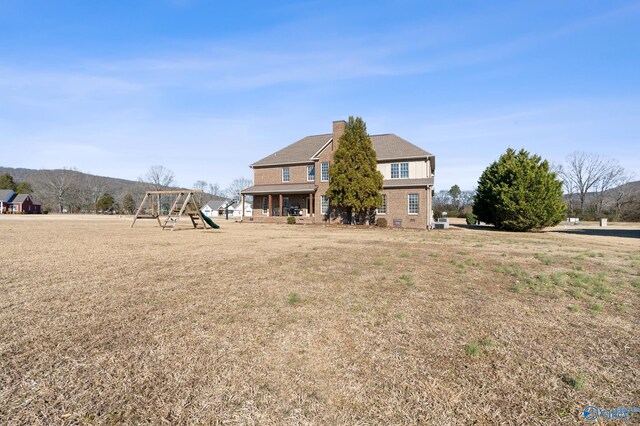 rear view of property featuring a mountain view and a playground