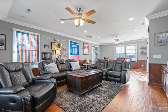 living room with ceiling fan, wood walls, crown molding, and wood-type flooring