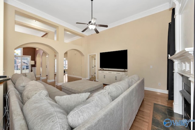 living room featuring ceiling fan, beam ceiling, wood-type flooring, and ornamental molding