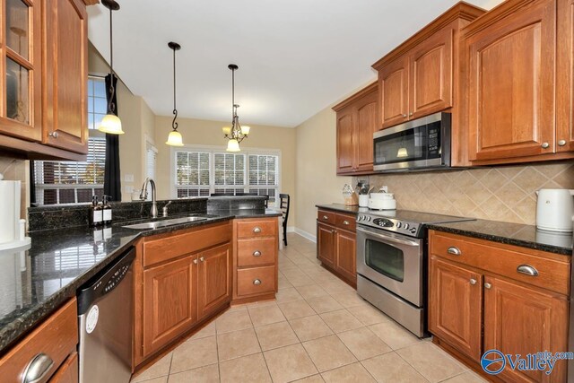 kitchen with sink, dark stone countertops, a chandelier, decorative light fixtures, and appliances with stainless steel finishes