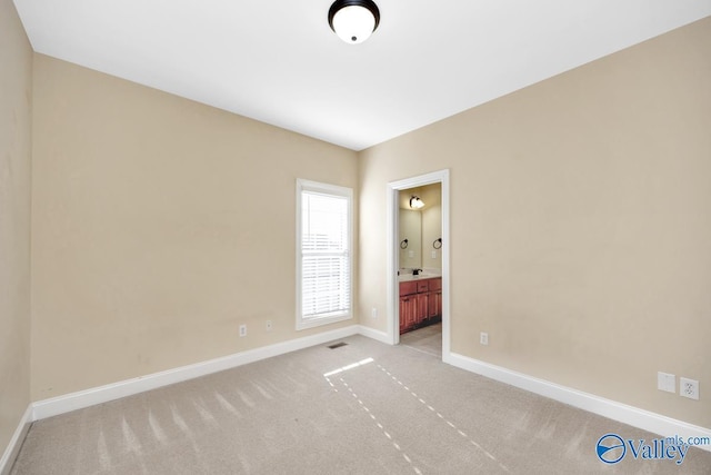 unfurnished bedroom with light colored carpet and ensuite bath