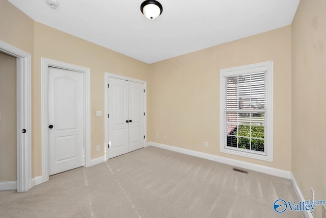 unfurnished bedroom with multiple closets and light colored carpet