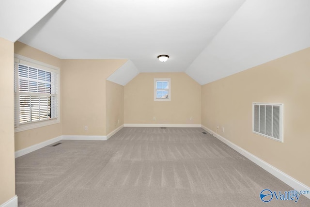 additional living space with plenty of natural light, light carpet, and vaulted ceiling