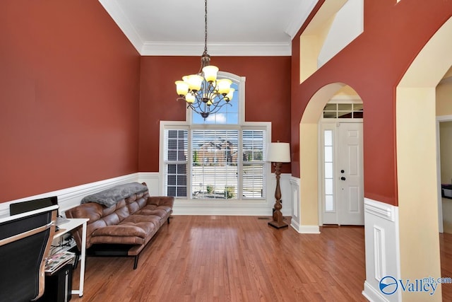 foyer entrance with hardwood / wood-style floors, a towering ceiling, ornamental molding, and a notable chandelier