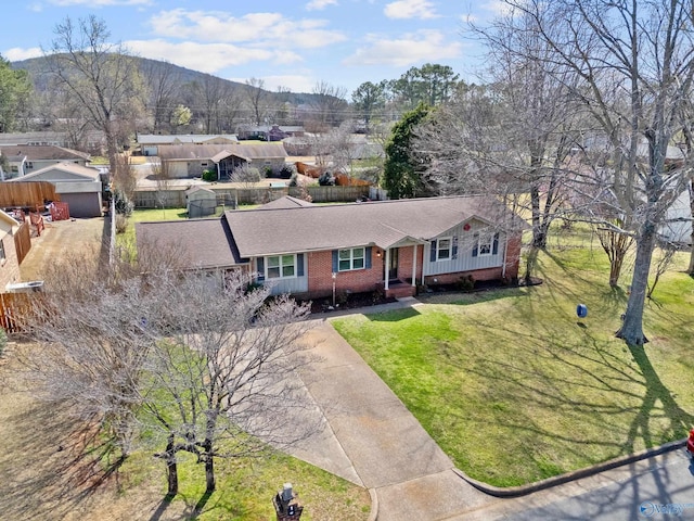 view of front facade featuring brick siding, driveway, a mountain view, and a front yard