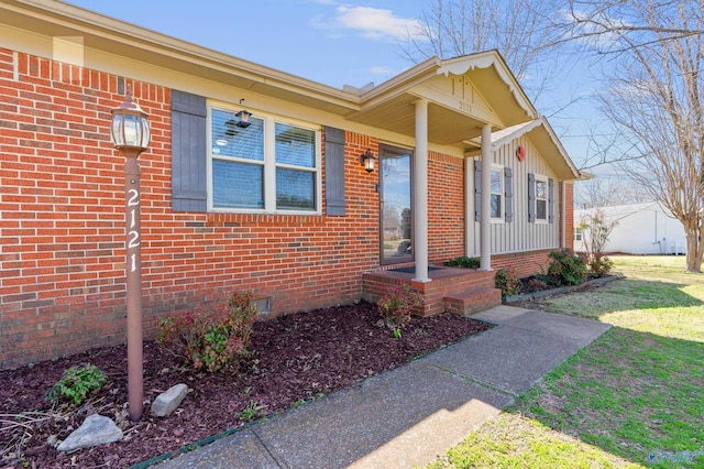 entrance to property with crawl space, a lawn, and brick siding