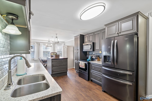 kitchen featuring a sink, stainless steel appliances, dark wood-type flooring, backsplash, and light stone counters