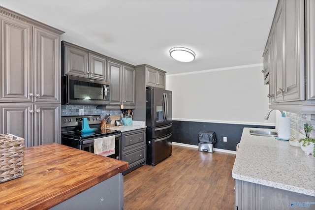 kitchen with stainless steel appliances, butcher block countertops, a sink, and backsplash