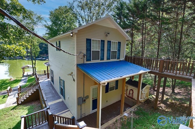 back of property with stairway, metal roof, and a deck with water view