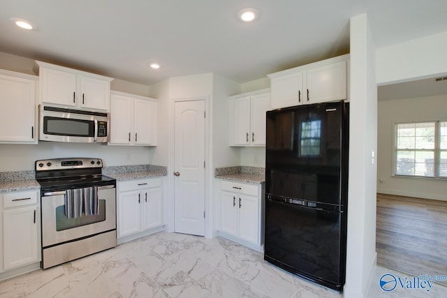 kitchen featuring white cabinetry, stainless steel appliances, and light stone countertops