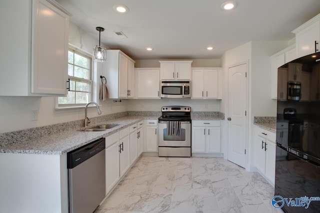 kitchen featuring white cabinetry, appliances with stainless steel finishes, sink, and hanging light fixtures