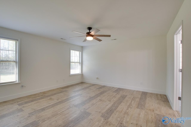 empty room featuring ceiling fan, plenty of natural light, and light hardwood / wood-style flooring