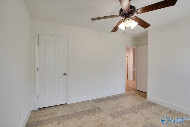 empty room with light wood finished floors, a ceiling fan, and baseboards