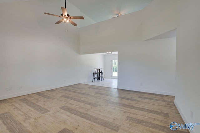 unfurnished living room featuring ceiling fan, light wood-type flooring, and high vaulted ceiling