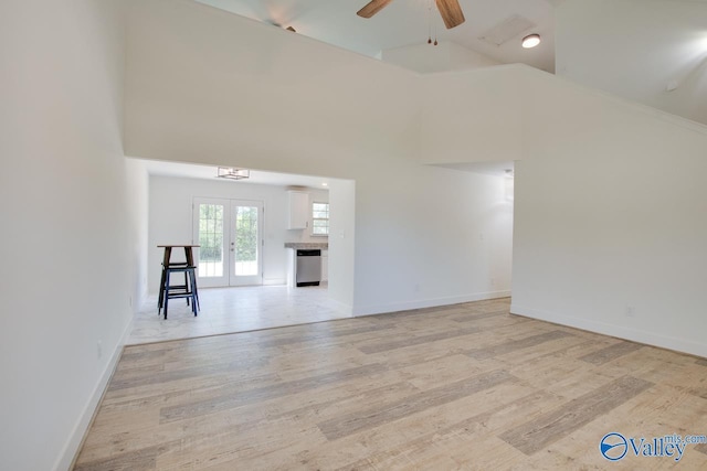 unfurnished living room with french doors, ceiling fan, high vaulted ceiling, and light hardwood / wood-style flooring