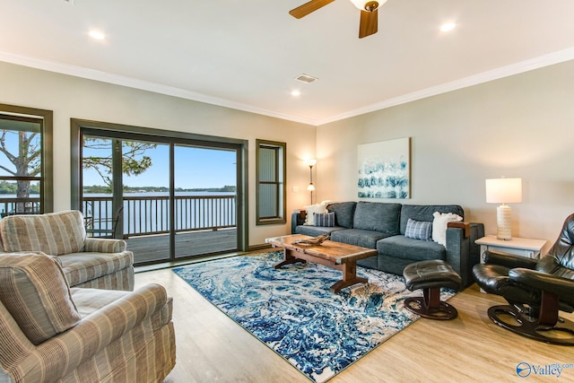 living room featuring crown molding, visible vents, a water view, ceiling fan, and wood finished floors