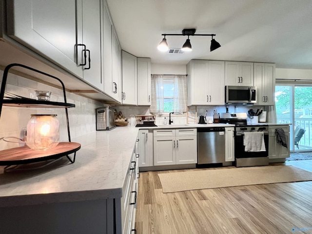 229 Crawford Rd, Scottsboro, AL 35769 - kitchen featuring a sink, light wood-style floors, backsplash, appliances with stainless steel finishes, and visible vents