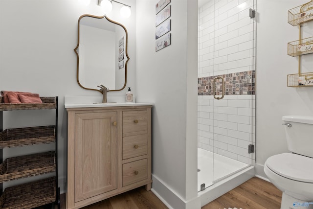 bathroom with hardwood / wood-style floors, vanity, an enclosed shower, and toilet