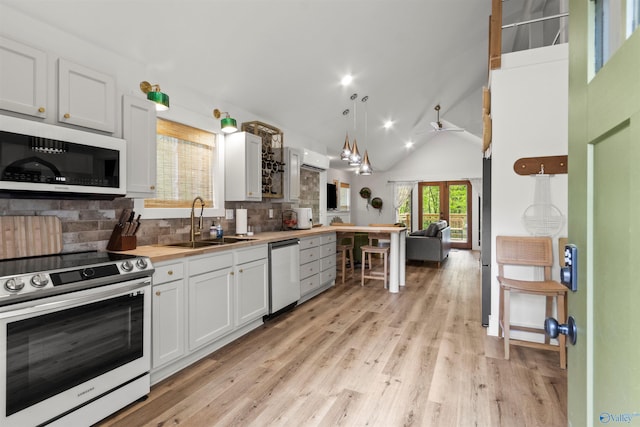 kitchen with sink, appliances with stainless steel finishes, decorative light fixtures, light hardwood / wood-style floors, and white cabinetry