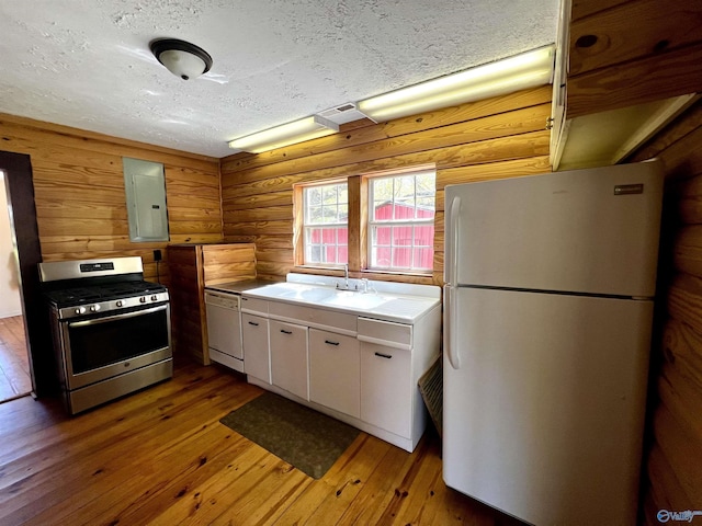 kitchen with electric panel, white appliances, white cabinets, and hardwood / wood-style flooring
