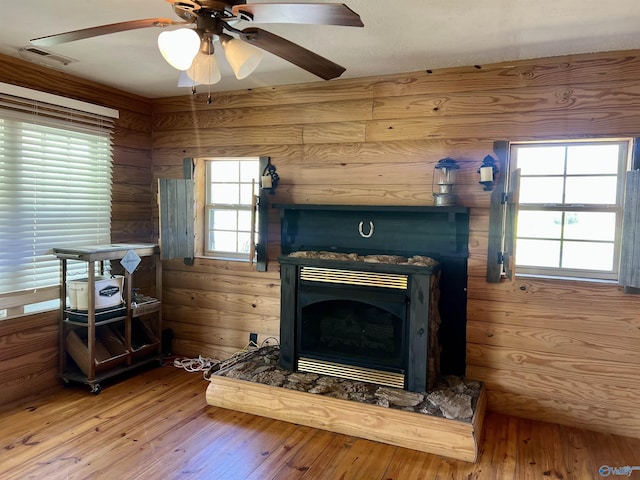 interior space with wood walls, visible vents, hardwood / wood-style floors, and ceiling fan