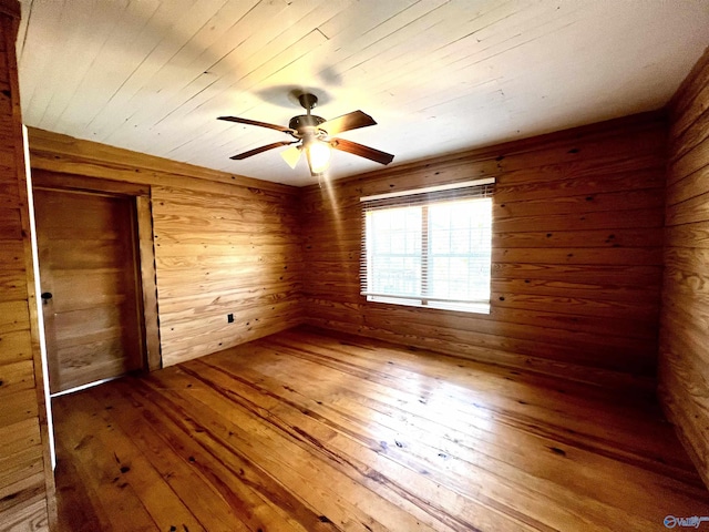 spare room with wood ceiling, wood walls, ceiling fan, and hardwood / wood-style flooring