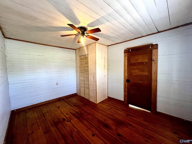 unfurnished bedroom featuring wooden ceiling, dark wood-type flooring, wooden walls, and a ceiling fan