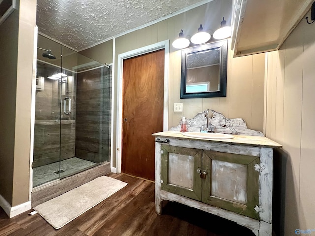 full bathroom featuring a shower stall, a textured ceiling, and wood finished floors