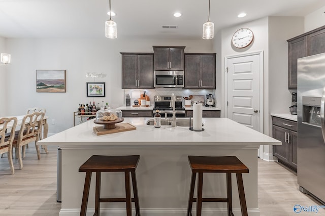 4018 SE Rockland Cir, Owens Cross Roads, AL 35763 - kitchen featuring appliances with stainless steel finishes, a breakfast bar area, dark brown cabinetry, tasteful backsplash, and recessed lighting