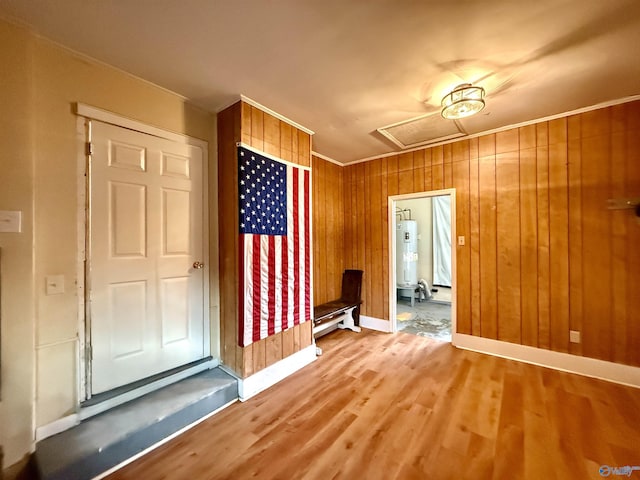 interior space featuring electric water heater, crown molding, wood-type flooring, and wooden walls