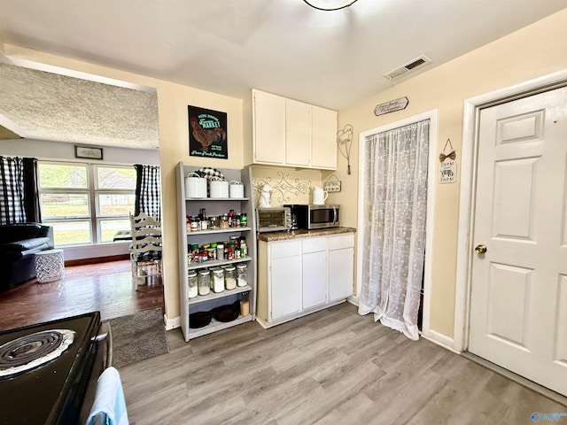 kitchen featuring white cabinetry, range with electric stovetop, and light hardwood / wood-style flooring