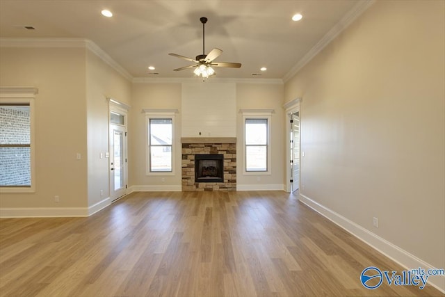 unfurnished living room with a wealth of natural light, ceiling fan, a fireplace, and ornamental molding