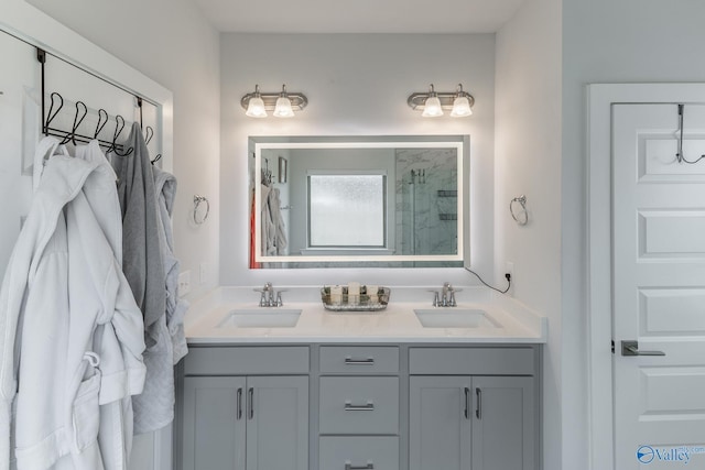 bathroom with double vanity, a sink, and tiled shower