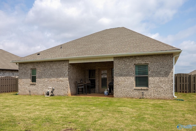back of house featuring fence, a patio, brick siding, a shingled roof, and a lawn
