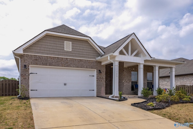 view of front of house featuring covered porch, driveway, brick siding, fence, and a shingled roof