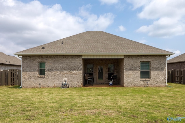 back of property featuring fence, a patio, brick siding, a shingled roof, and a lawn