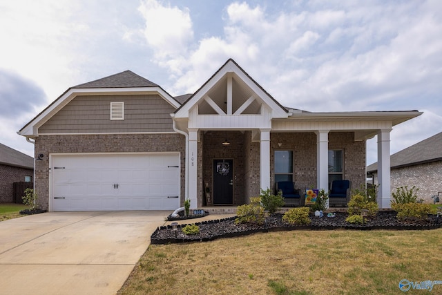 craftsman-style home featuring a porch, brick siding, a front yard, and concrete driveway