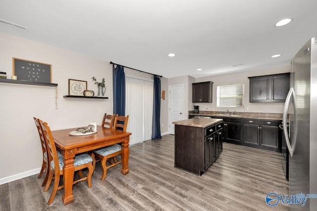 kitchen featuring a sink, visible vents, a kitchen island, light wood-style floors, and freestanding refrigerator