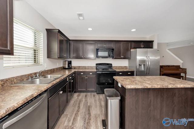 kitchen with a center island, light wood finished floors, a sink, dark brown cabinets, and black appliances