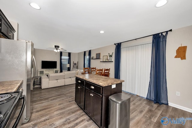 kitchen with black electric range, open floor plan, wood finished floors, and recessed lighting