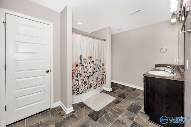 bathroom with double vanity, baseboards, visible vents, a shower with curtain, and a sink