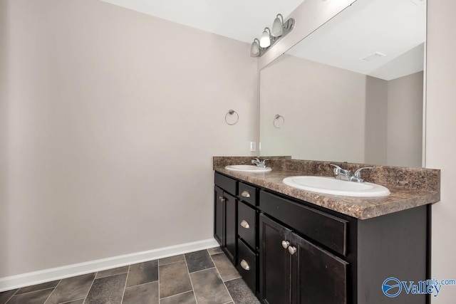 full bathroom featuring a sink, baseboards, and double vanity