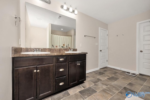 bathroom with double vanity, a sink, visible vents, and baseboards