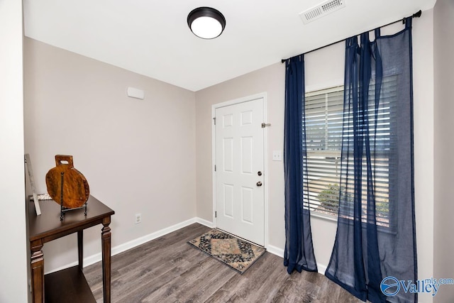 foyer entrance featuring baseboards, visible vents, and wood finished floors